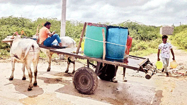 హెబ్బటం గ్రామంలో ఎద్దుల బండిపై డ్రమ్ముల ద్వారా నీరు తీసుకెళ్తున్న ప్రజలు 