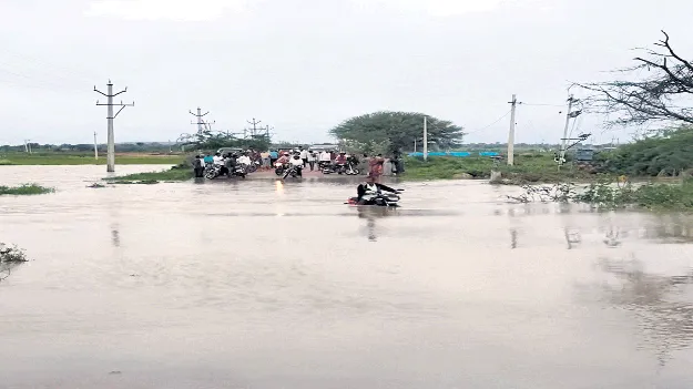 అలుగు పారిన చెరువు.. ప్రధాన రహదారిపైకి నీళ్లు 