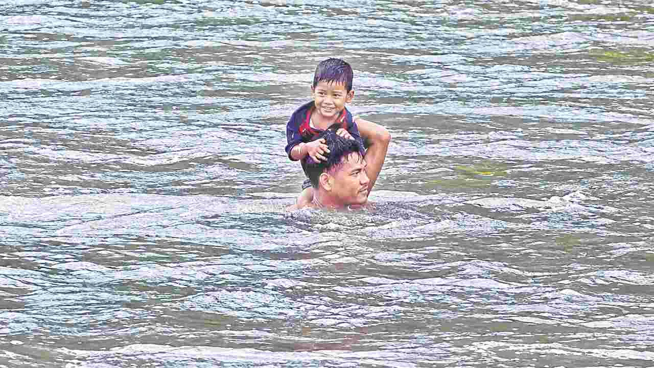 ప్రాణాలకు తెగించి.. బాలుడిని గెడ్డ దాటించి