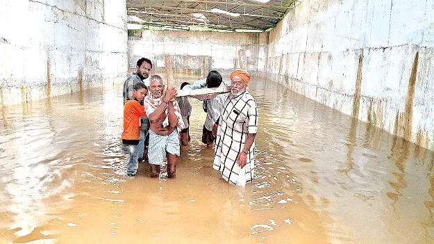 మంచంపై మోసుకుంటూ.. వరద నీటిని దాటించి
